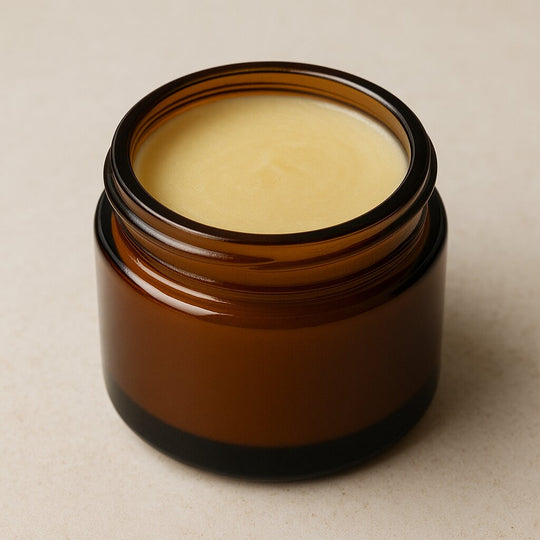 Amber glass jar with a light-colored balm inside on a beige background
