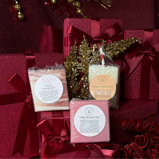 Three soaps in front of red gift boxes with decorative elements